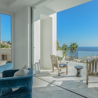 Relax in your stylish living space with floor-to-ceiling windows opening to a private terrace overlooking stunning ocean views.