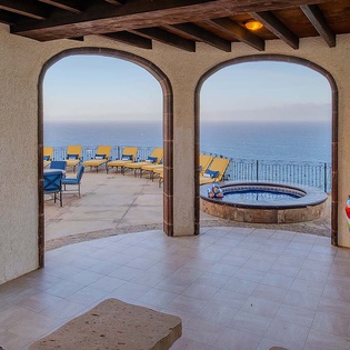 Expansive ocean views frame a private terrace, where you can unwind in a sparkling hot tub or lounge in comfort beneath authentic wooden beams as the sea stretches endlessly before you.