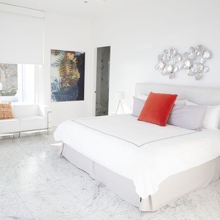 Sink into crisp white linens in your modern bedroom, where contemporary art and marble floors create a serene retreat.