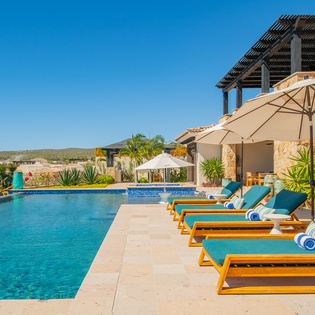 Luxurious poolside retreat with crystal-clear waters and comfortable loungers under sunny skies.