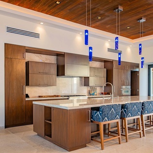Gather around this stunning kitchen island with stylish blue-patterned seating, modern appliances, and a striking wood ceiling that creates the perfect space for your culinary adventures and memorable meals together.