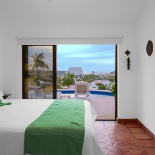 Wake up to stunning pool and tropical views from your bright bedroom, where colorful accents and terracotta floors create a warm, welcoming retreat.