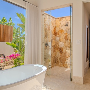 Soak in your luxurious freestanding tub with views of tropical gardens, then refresh in your stone-walled shower.
