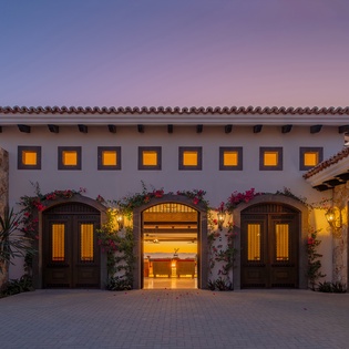 A stunning Spanish colonial villa featuring terra cotta tiles, stone accents, and warm lighting creates an enchanting arrival experience.