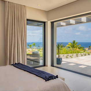 Wake up to breathtaking ocean views through floor-to-ceiling glass doors that open your room to the horizon. The gentle sea breeze and endless blue await just beyond your bed.