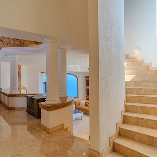 Soaring natural stone staircase and elegant columns welcome you into a luminous Mediterranean-inspired space, where sunlight filters through to reveal breathtaking ocean vistas.