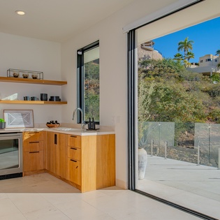 Your modern kitchen flows seamlessly to a private terrace, where warm wood cabinetry and sleek appliances create the perfect space for cooking meals.