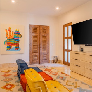 Relax in your vibrant living space featuring colorful artwork, comfortable seating, and modern entertainment setup with flat-screen TV.