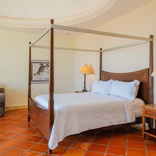 Sink into the inviting four-poster bed and relax on terracotta floors, with a cozy seating area and warm ambient lighting welcoming you after your day of adventure.