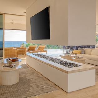 Unwind in your sophisticated living space featuring a stunning gas fireplace and breathtaking ocean views through floor-to-ceiling windows.