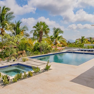 Sink into your poolside lounge under swaying palms, with a sparkling pool and hot tub ready for your refreshing escape in this tropical paradise.