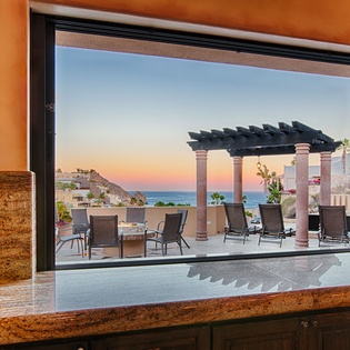 Framed ocean views await beyond this sleek window, opening to a serene terrace where your morning coffee meets coastal sunrises and evening relaxation finds the perfect backdrop.