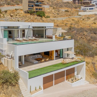 Modern multi-level villa nestled in dramatic desert hillside, featuring stunning contemporary architecture and outdoor terraces.