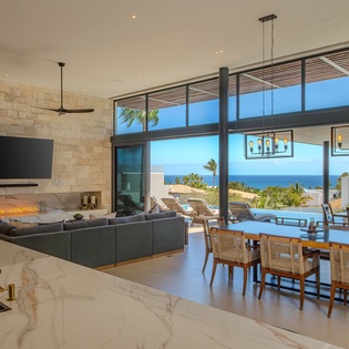 Your open-concept living space features floor-to-ceiling windows framing stunning ocean views, where modern luxury meets island tranquility.