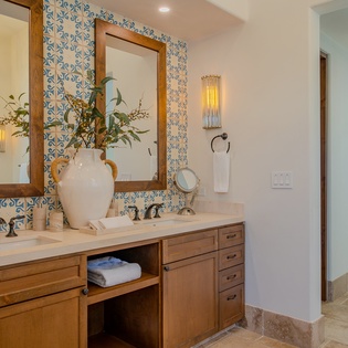 Pamper yourself in this stunning bathroom featuring hand-painted tiles, warm wood vanities, and thoughtful touches that create a spa-like retreat.