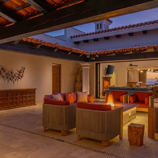 You'll love unwinding in this stunning outdoor living space, where warm firelight dances beneath exposed beams as twilight paints the sky.