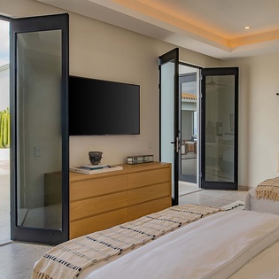 Step into your serene bedroom retreat, where floor-to-ceiling glass doors open directly to the terrace, flooding the space with natural light and desert breezes.