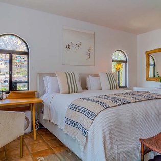 Sink into crisp linens and soft throws as natural light pours through arched windows, framing peaceful water views that greet you each morning.