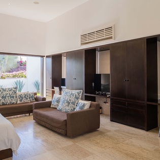 Settle into your comfortable suite where sleek furnishings meet tropical ease. Glass doors frame lush greenery, while climate control keeps you perfectly cool as you unwind.