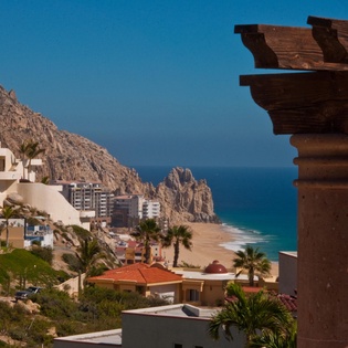This coastal property offers stunning views of dramatic rock formations meeting turquoise waters, with golden sand beaches stretching along the horizon in a picturesque seaside setting.