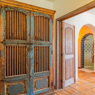 Step into a space where rustic charm meets vibrant character—weathered wood doors open to terracotta warmth and handcrafted archways invite you to explore your tranquil retreat.