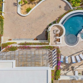 The property features a sparkling pool surrounded by lush tropical gardens, poolside lounge chairs, and an integrated hot tub, creating an inviting outdoor oasis for relaxation.