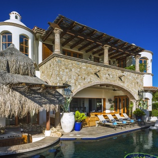 Stunning Mediterranean villa with private pool, outdoor kitchen, and stone architecture set against brilliant blue skies.