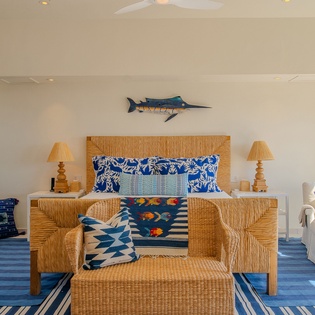 Your coastal-inspired bedroom features vibrant blue textiles, wicker furniture, and charming nautical touches that create the perfect seaside retreat.