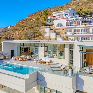 Modern hillside villa with infinity pool showcases sleek architecture against coastal landscape.