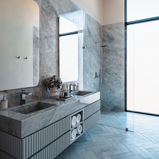 Luxurious marble bathroom with rainfall shower, dual vanity, and floor-to-ceiling windows creating your perfect spa retreat.