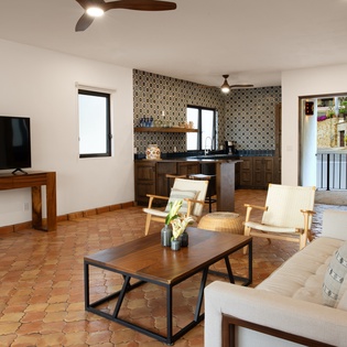 Unwind in your stylish open-plan living space featuring handcrafted tile floors, geometric kitchen backsplash, and comfortable seating perfect for relaxation.