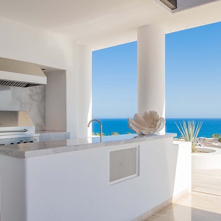 Prepare meals while taking in the stunning ocean views from this bright, modern outdoor kitchen complete with grill and sleek countertops.