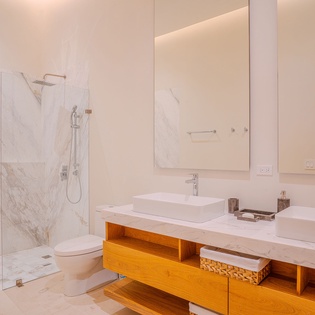 Indulge in your private spa-like bathroom featuring luxurious marble walls, a spacious walk-in shower, and elegant double vanities with warm wood accents.