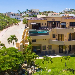 Stunning hillside villa with pool terrace set in a vibrant coastal neighborhood, surrounded by lush landscaping and palm trees—a perfect vacation retreat.