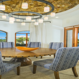 Gather around your gorgeous dining table under dramatic pendant lighting, where tropical views frame every meal and conversation flows as smoothly as the curves above.