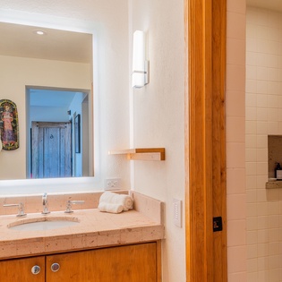 Step into your spa-like bathroom featuring warm wood accents, elegant stone counters, and a spacious walk-in shower perfect for unwinding.
