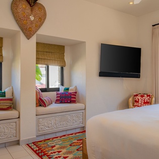 Unwind in your charming bedroom featuring cozy window nooks, vibrant textiles, and peaceful views through bamboo shades.