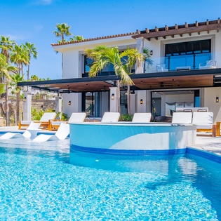 Modern beachfront villa with stunning blue pool, tropical palms, and contemporary design creating the perfect luxury retreat.