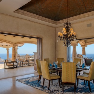 Your elegant dining room showcases ocean views through floor-to-ceiling windows, perfect for memorable meals with sophisticated furnishings and stunning terrace access.
