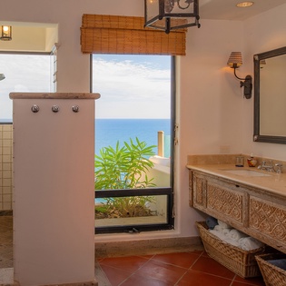 En suite bathroom with double sinks, walk in shower, and ocean views