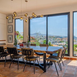 A spacious dining area with panoramic city and ocean views, featuring a large communal table perfect for gathering with friends and family.