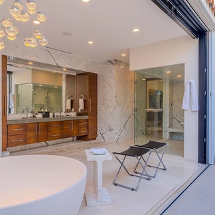 Indulge in your private spa-like sanctuary with a freestanding soaking tub, modern vanity, and seamless indoor-outdoor access to your secluded patio.