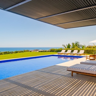 Beautiful patio with lounge chairs by the pool and ocean views