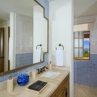 Refresh in your elegant bathroom featuring beautiful blue mosaic tile accents, marble countertops, and pristine white towels awaiting your arrival.