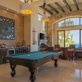 Unwind in your stunning game room with billiards, wet bar, and breathtaking sea views through stone arches.
