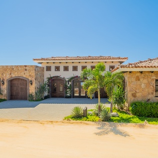 Stunning Mediterranean villa with stone facade, red tile roof, and tropical landscaping creates an impressive arrival experience.