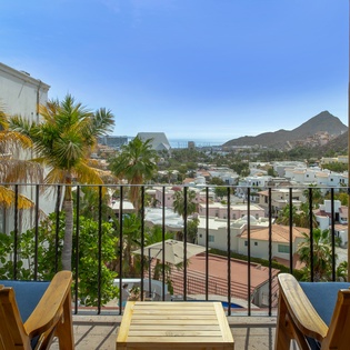 Soak up panoramic mountain and city views from your private balcony with comfortable seating and tropical palms.