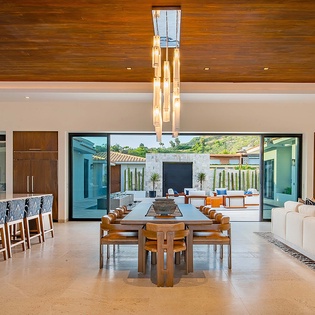Step into an open-concept living and dining space where warm wood tones meet modern design. Large glass doors frame your private courtyard oasis, blending indoor luxury with serene outdoor living.