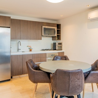 Gather around your stylish dining table in this modern kitchen space, where sleek appliances and warm wood tones create the perfect setting for meals.