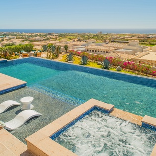 Stunning infinity pool with bubbling spa overlooks rolling hills to distant ocean views—a perfect desert oasis retreat.